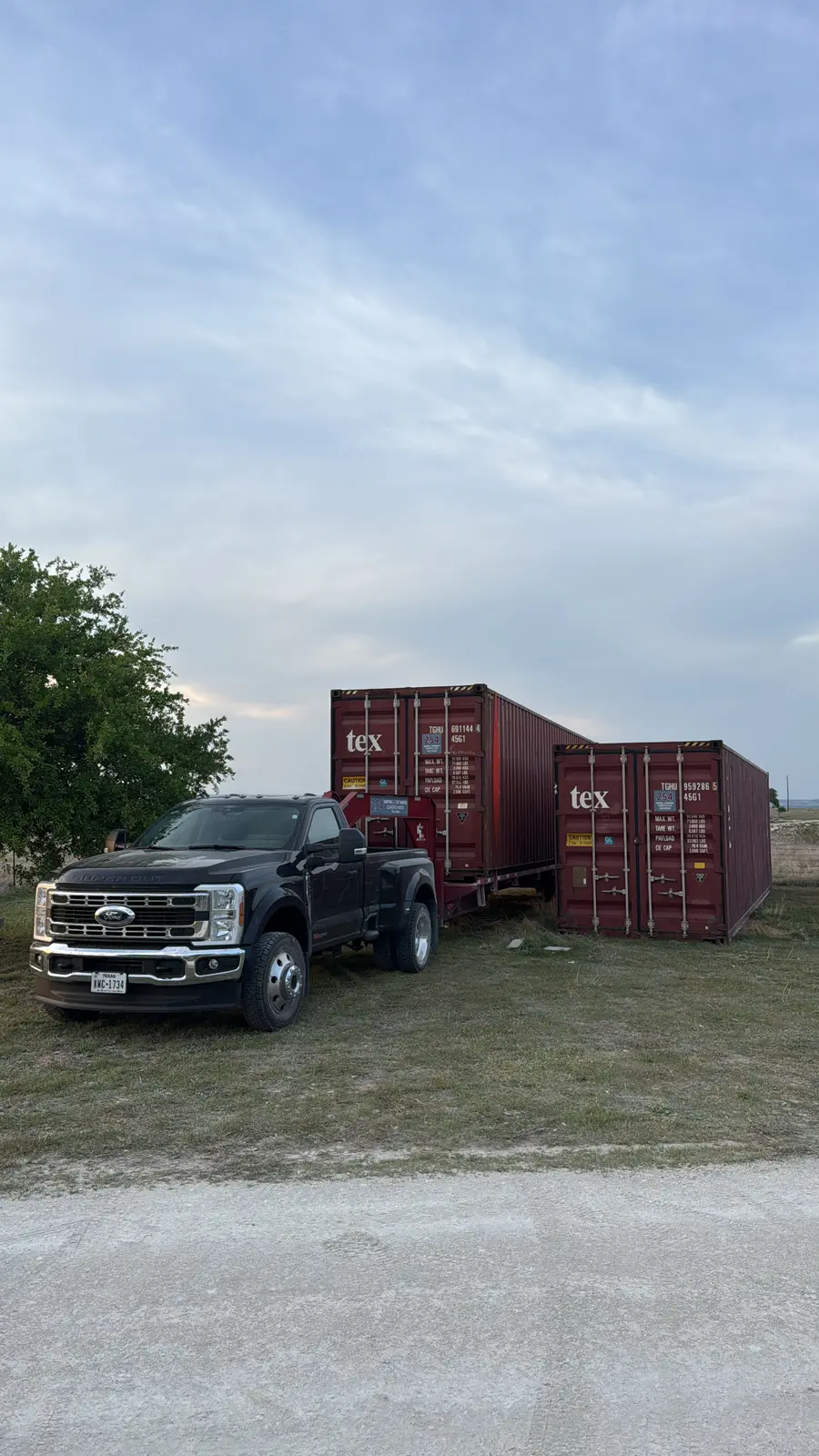 Black Ford F-450 beside two red 40-foot high-cube cargo-worthy containers
