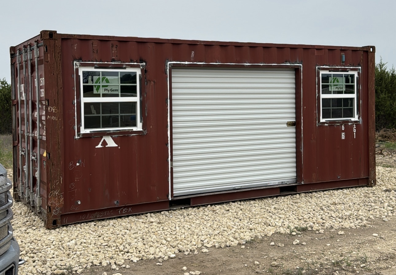 Red shipping container modified with a large roll-up door and two windows
