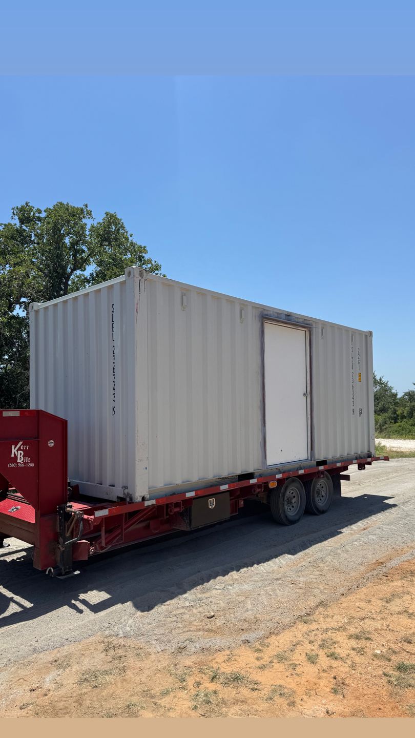 Light-colored shipping container with a steel personnel door on its side