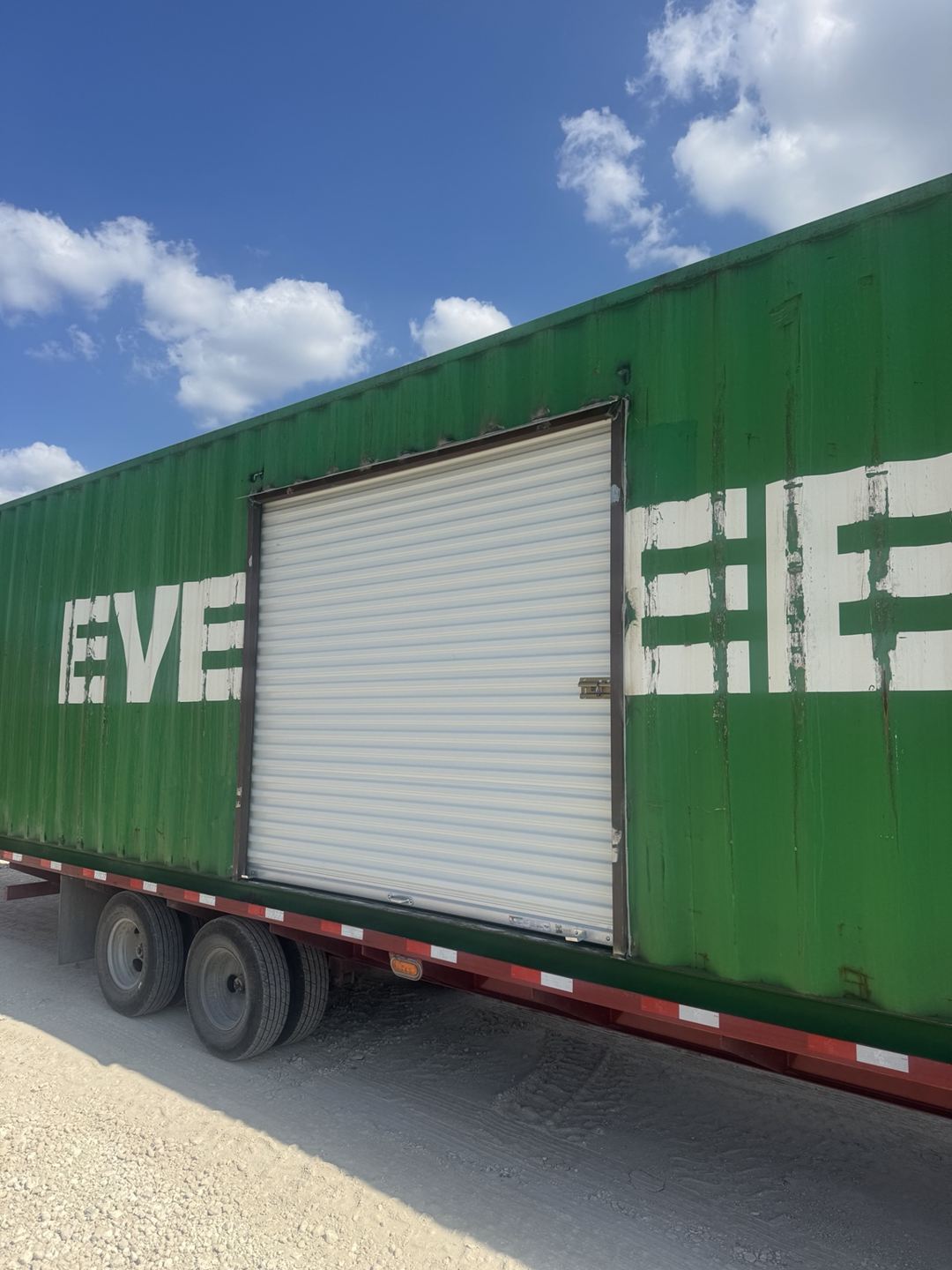 Green container with a large roll-up door installed in its sidewall