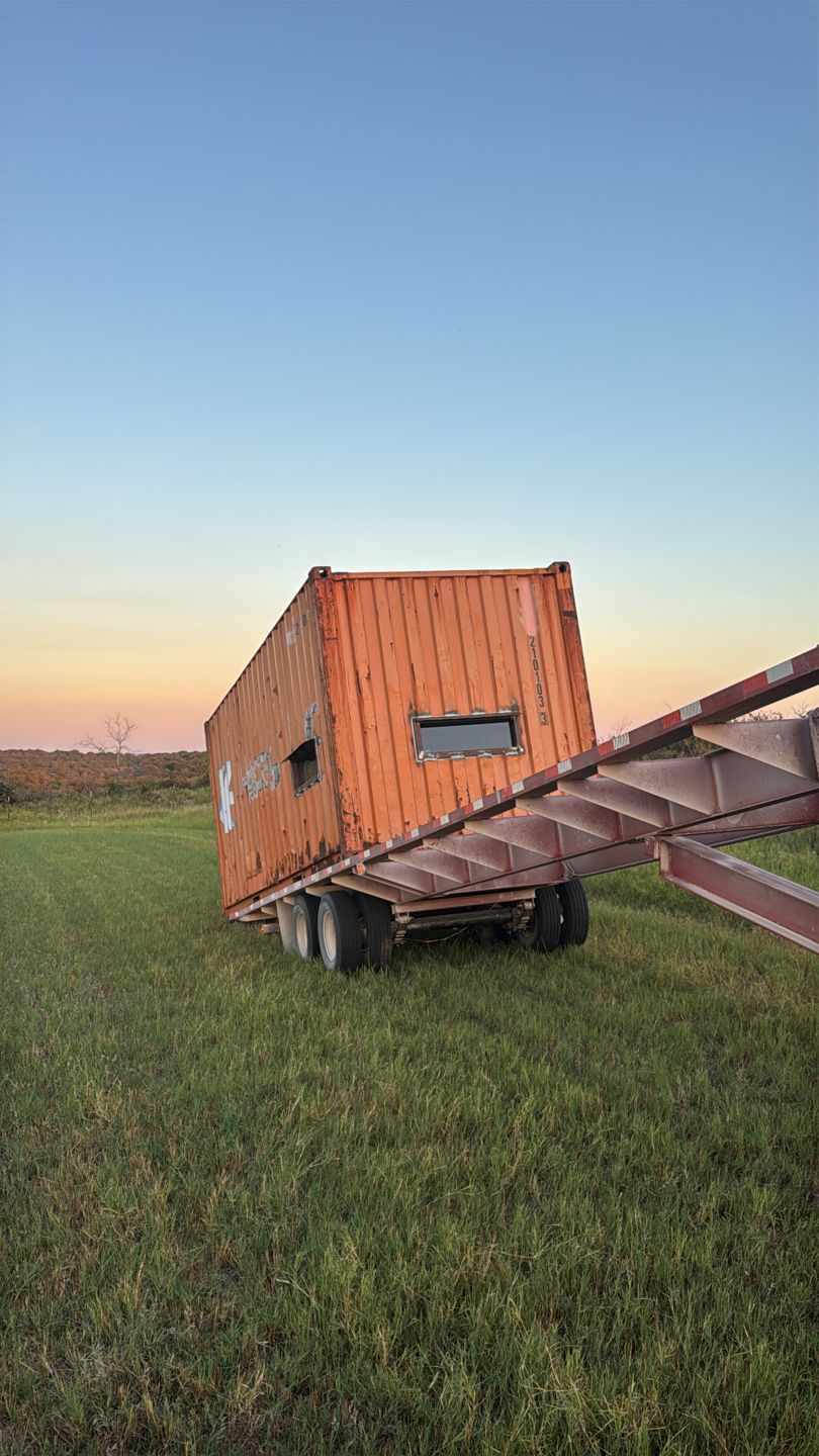 Orange modified container with small windows on a tilt trailer