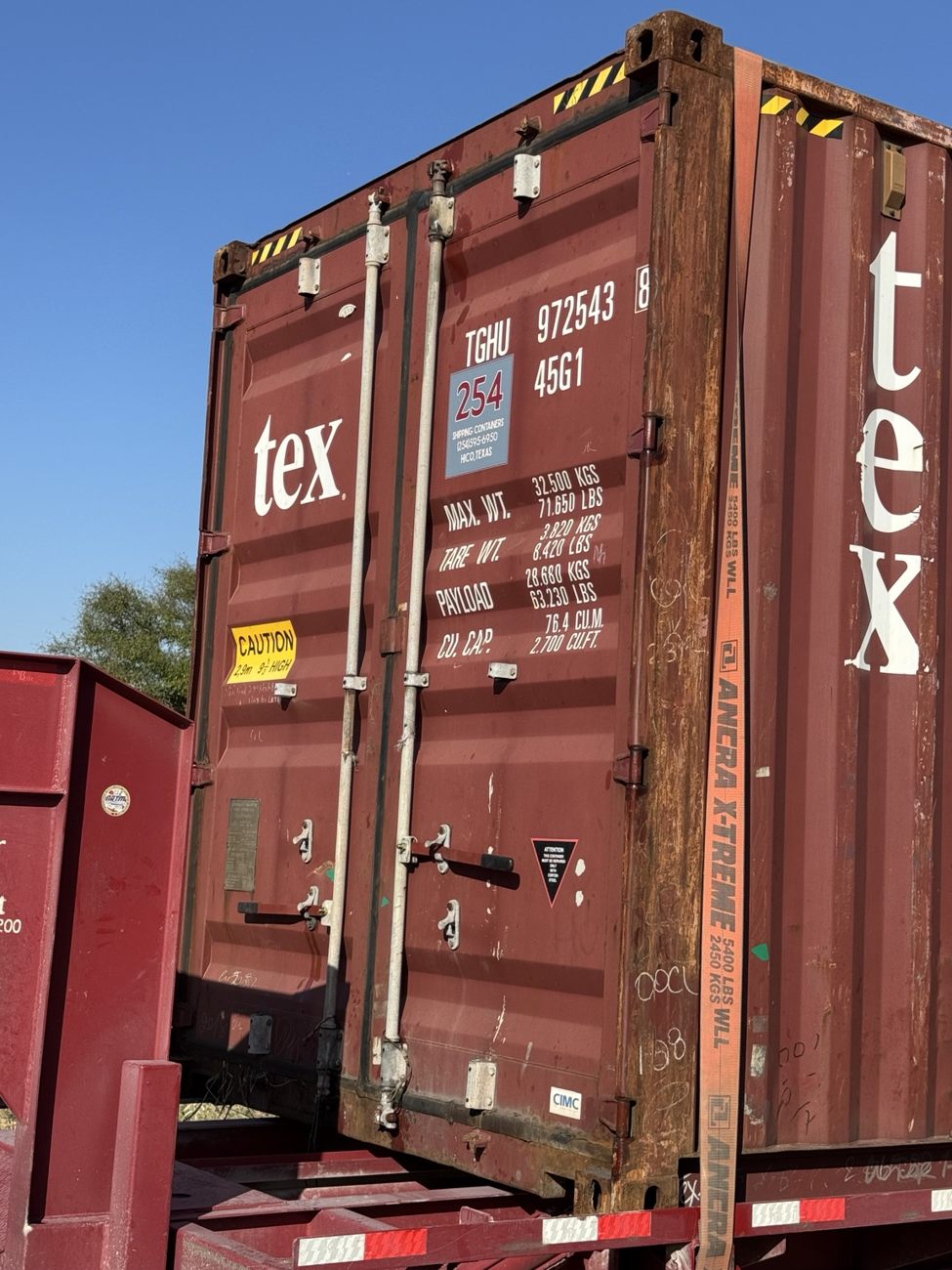 Used red shipping container with retrofit handles on the cargo doors