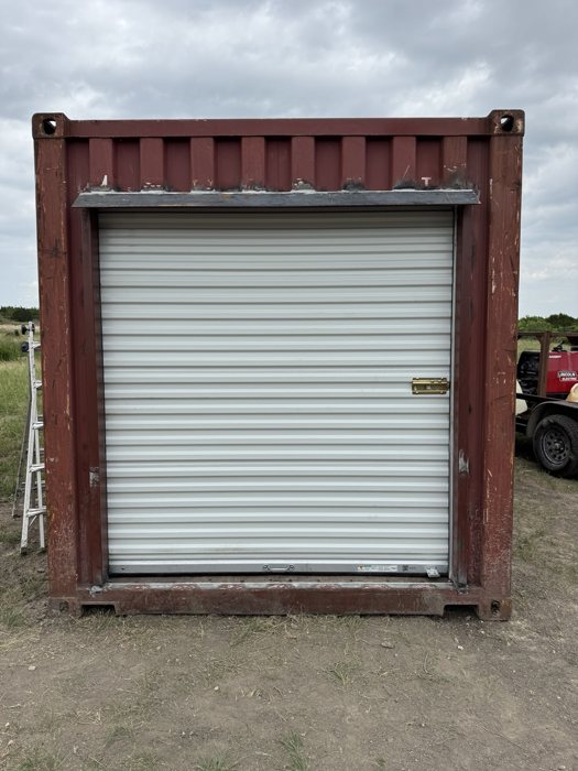 White roll-up door installed in the end of a red shipping container