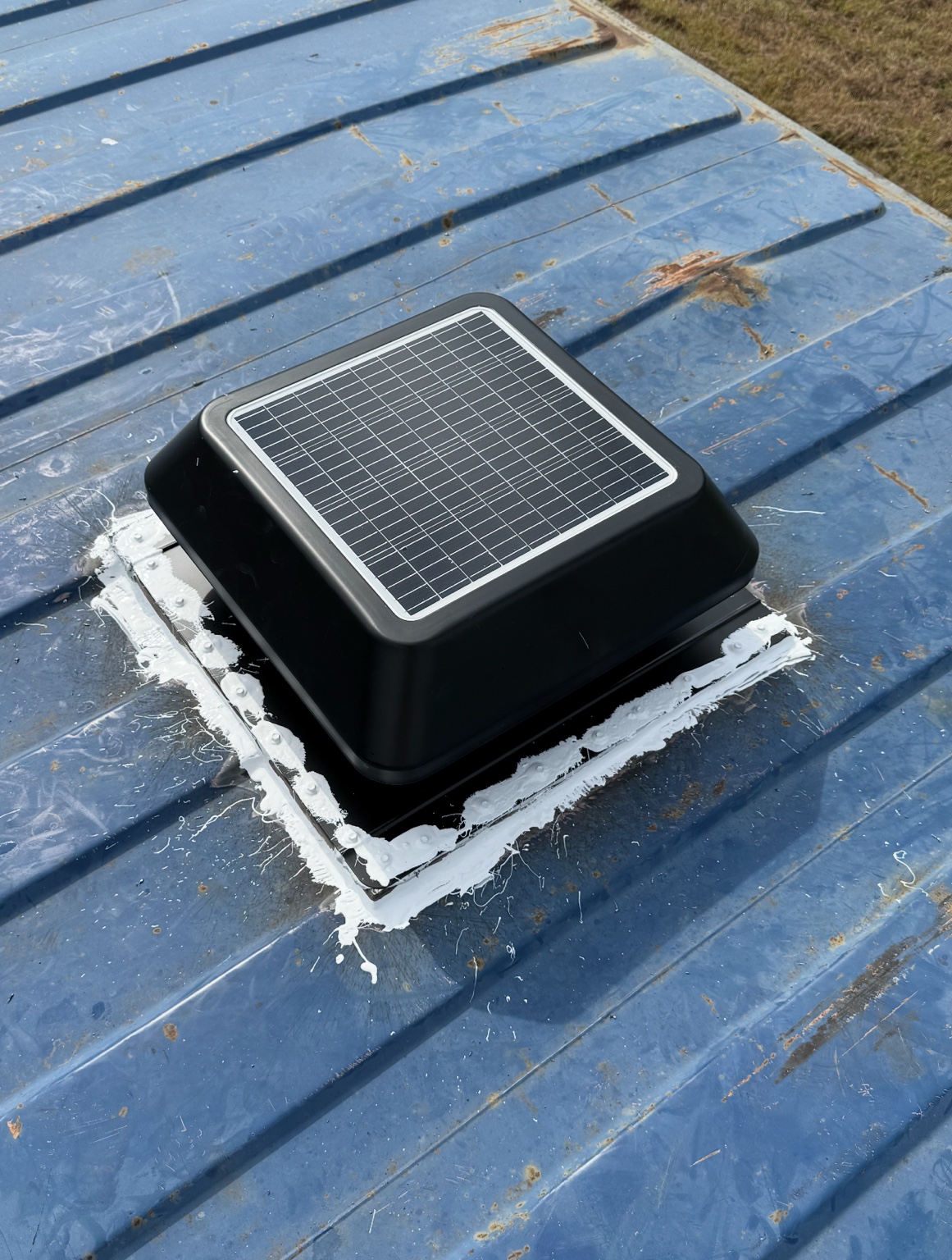 Black solar vent installed on a blue shipping container roof