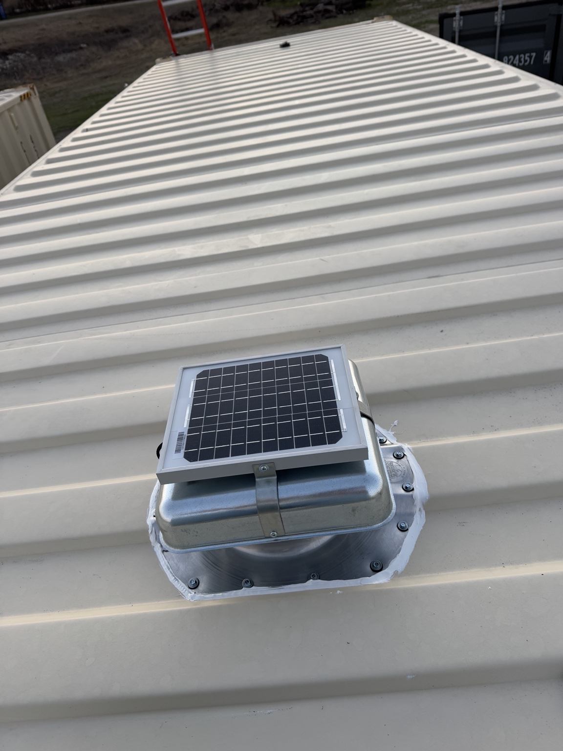 Silver solar-powered vent installed on a light-colored shipping container roof