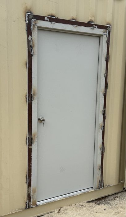 White steel personnel door installed in a beige shipping container