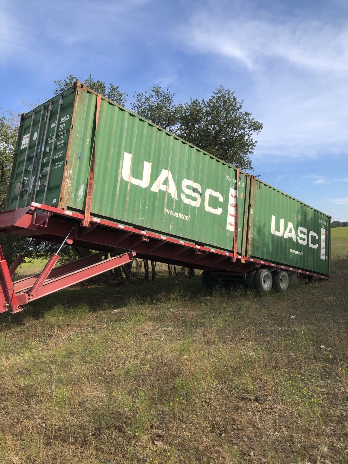 Two 20-foot shipping containers transported together on one 40-foot tilt-bed trailer